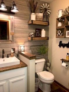 a white toilet sitting next to a sink in a bathroom under two wooden shelvings