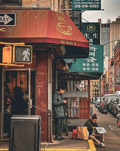 a man sitting on the sidewalk in front of a coffee shop