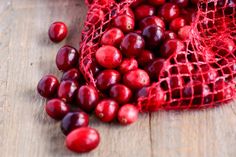 a red bag full of cherries sitting on top of a wooden table