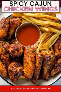 spicy cajun chicken wings on a plate with french fries and ketchup sauce