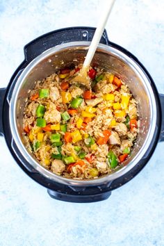 an overhead view of rice and vegetables cooking in the instant pot with a wooden spoon