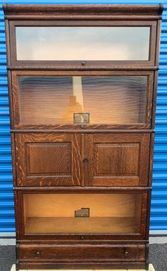 an old wooden dresser with glass doors on it's sides in front of a blue wall