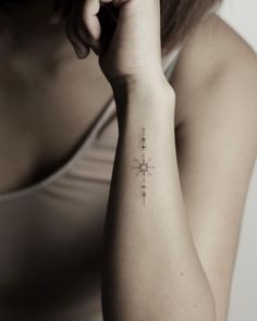 a woman with a small cross tattoo on her left arm and right arm behind her head