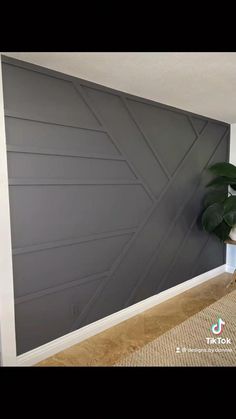 a living room with a plant in the corner and a gray wall behind it that has been painted