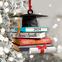 a graduation ornament hanging from a tree with books stacked on top of each other