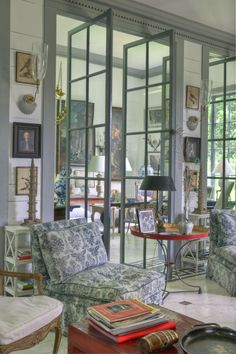 a living room filled with lots of furniture next to large glass doors that lead into the outside