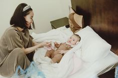 a woman is feeding her baby in bed