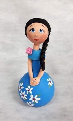 a little doll sitting on top of a blue ball with flowers in it's hair