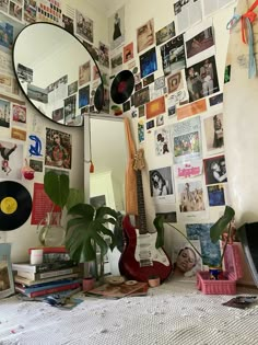 a room with many pictures on the wall and a guitar in front of a mirror