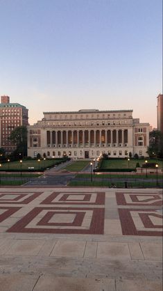 a large building with many windows and lights on it's sides in the evening