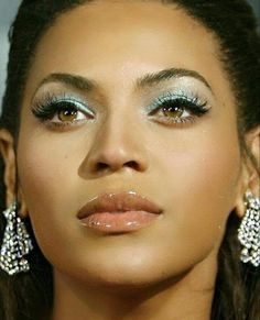 a close up of a woman with makeup on her face and wearing green eyeliners