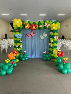 a balloon arch decorated with flowers and butterflies