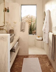 a bathroom with white walls and tile flooring, along with a cactus in the window