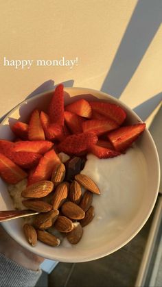 a bowl filled with almonds and strawberries on top of a table