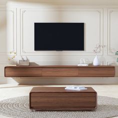 a living room with a large flat screen tv mounted on the wall above a wooden coffee table