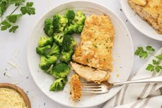 a white plate topped with chicken and broccoli next to a bowl of noodles