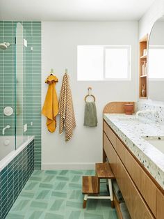 a bathroom with green tile and wooden cabinets