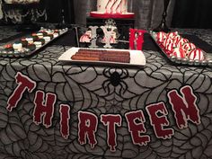 a table topped with lots of cakes covered in red and white frosting on top of a black table cloth