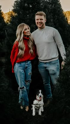 a man and woman standing next to each other with a dog