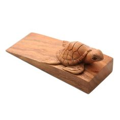 a wooden turtle figurine sitting on top of a piece of wood with a white background