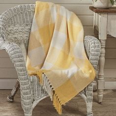 a chair with a yellow and white checkered blanket on it next to a potted plant