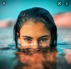 a close up of a woman's face in the water with her eyes wide open