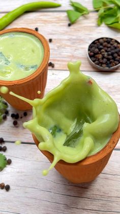 two cups filled with green liquid next to some beans