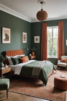 a bedroom with dark green walls and orange drapes on the windowsill, an upholstered bed in front of a large window