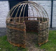 two round baskets sitting on the grass near a brick wall and fenced in area