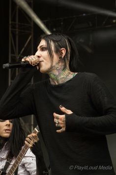 a man with black hair and piercings on his face holding a guitar in front of him