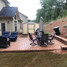 a patio with chairs and an umbrella next to a house