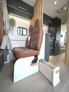 the interior of an rv with brown leather seats and storage boxes on the floor next to it