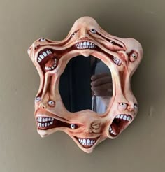 a strange looking mirror hanging on the side of a wall with fake teeth and mouths