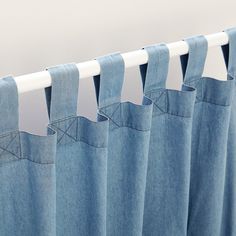 blue jeans hanging on a curtain rod in front of a white wall, with the curtains pulled back