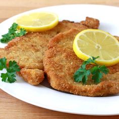 fried fish with parsley and lemon slices on a white plate