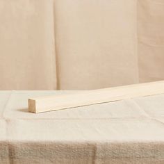 a piece of wood sitting on top of a white cloth covered tablecloth next to a window