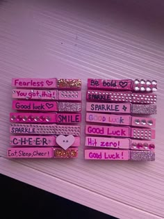 pink and gold hair clips with words on them