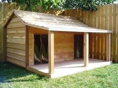 a dog house built into the side of a fenced in area with grass and trees