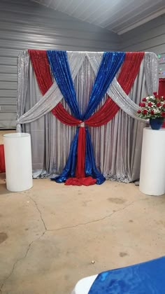 a red, white and blue stage set up for an event with flowers in vases