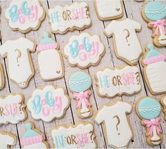 baby shower cookies are arranged on a wooden table with pink and blue decorations, including ones that say it's girl