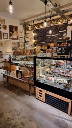 the inside of a bakery with lots of food on display in it's glass case