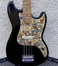 an electric guitar is sitting on top of a wire rack and has a colorful floral design on it