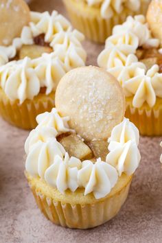 several cupcakes with white frosting and toppings