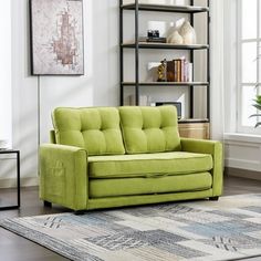 a green couch sitting on top of a rug next to a book shelf filled with books