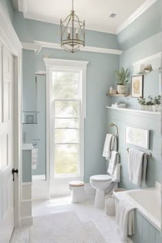 a bathroom with blue walls and white fixtures, including a chandelier above the toilet