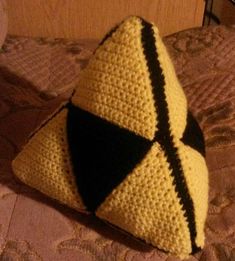 a crocheted triangle pillow sitting on top of a bed