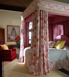 a canopy bed in a bedroom with pink curtains