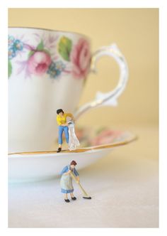 miniature figurines sitting on top of a tea cup