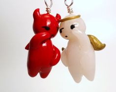 two red and white plastic items hanging from hooks on strings, one with a gold - plated earring