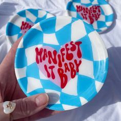 two plates with words on them that say,'manfest it baby'in red and blue checkerboard